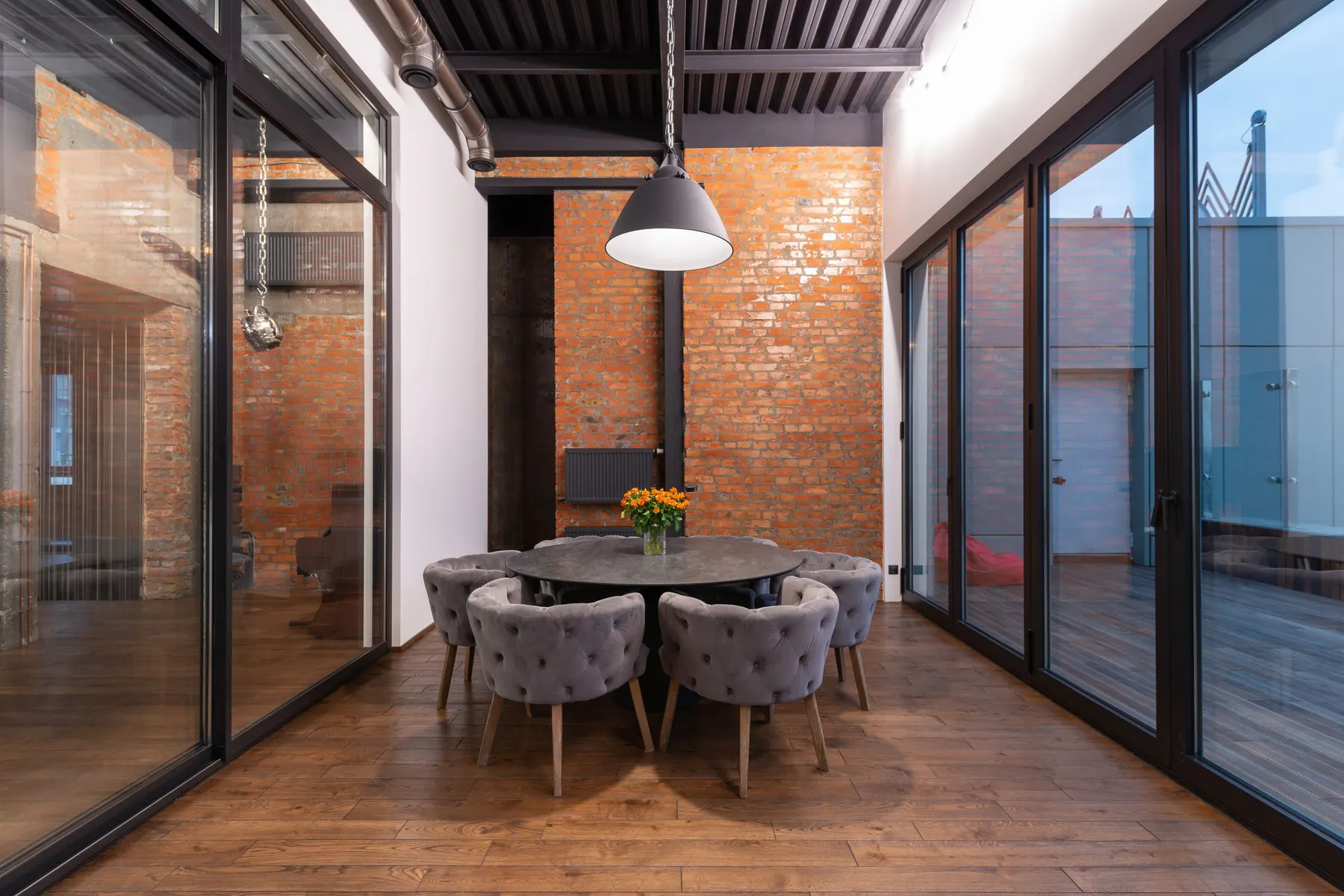 Comedor con carpintería antracita de suelo a techo en dos frentes y cielo cubierto al otro lado. Con luz gris la mayor parte del año, cada metro de vidrio cuenta para la luz natural del interior.