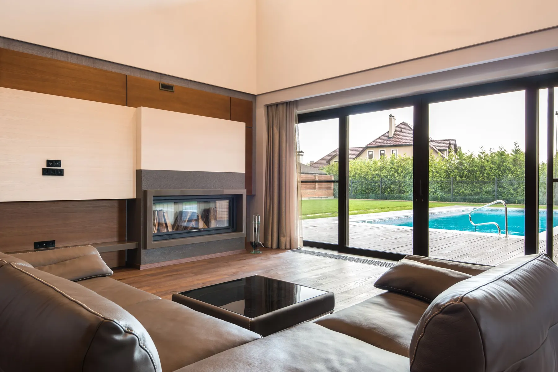 Salón con corredera de gran formato en perfil oscuro abierta a una terraza exterior. Con hojas de este tamaño, la diferencia entre arrastrar y elevar se nota cada vez que se abre.